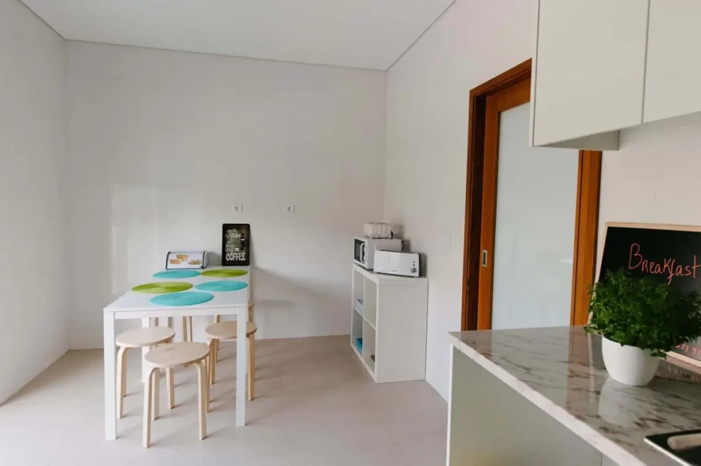 Dining room table and chairs, with a microwave next to them.