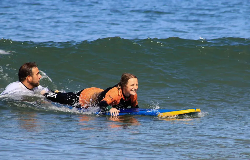 Secret Surf instructor helping a young surfer to catch her first wave.
